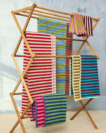["Colorful striped towels on a wooden drying rack against a light gray wall. ", " Put us in a cup (your cart) and take us outside (home)"]