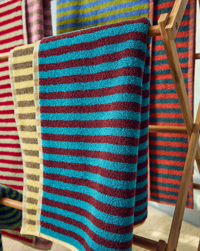 Dragonfly towel in yellow, beige, maroon and blue hanging on wooden rack