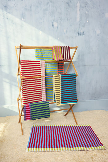 Colorful striped towels on a wooden towel rack against a gray wall. 