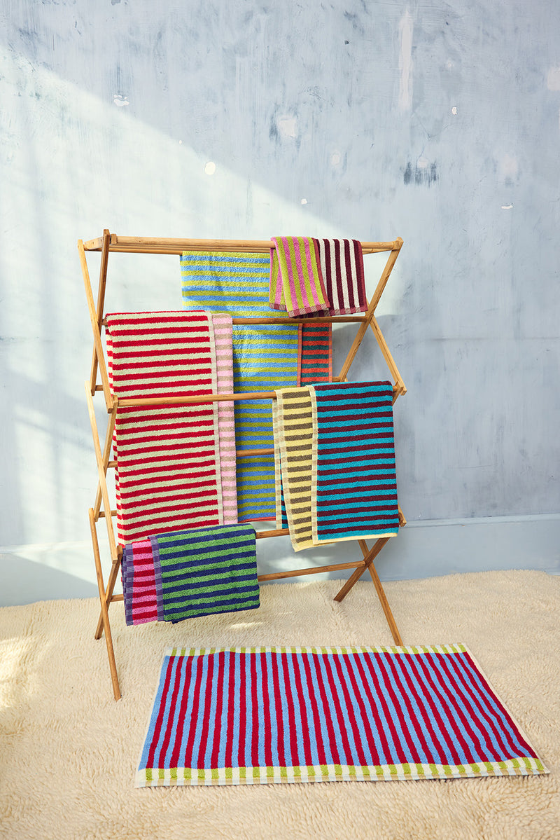 Colorful striped towels on a wooden towel rack against a gray wall. 