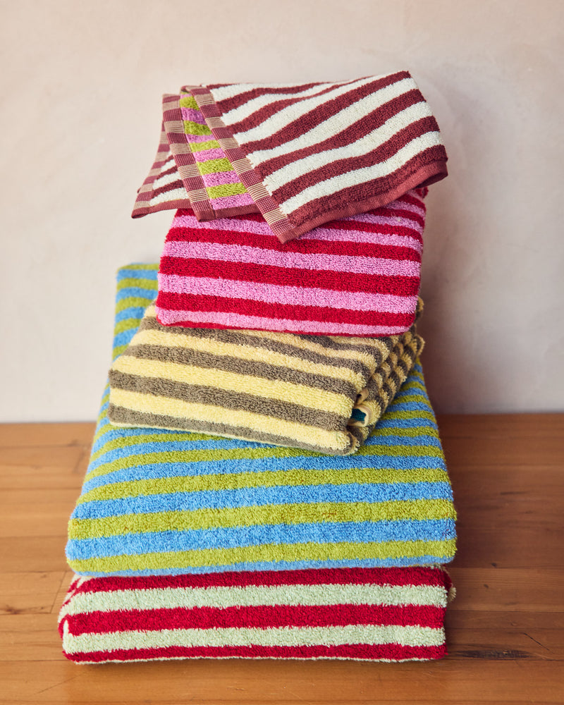 Stack of colorful striped towels on a wooden surface with a plain background