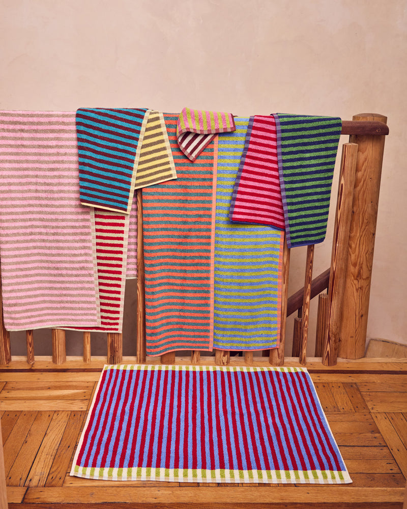 Colorful striped towels hanging on a wooden railing.