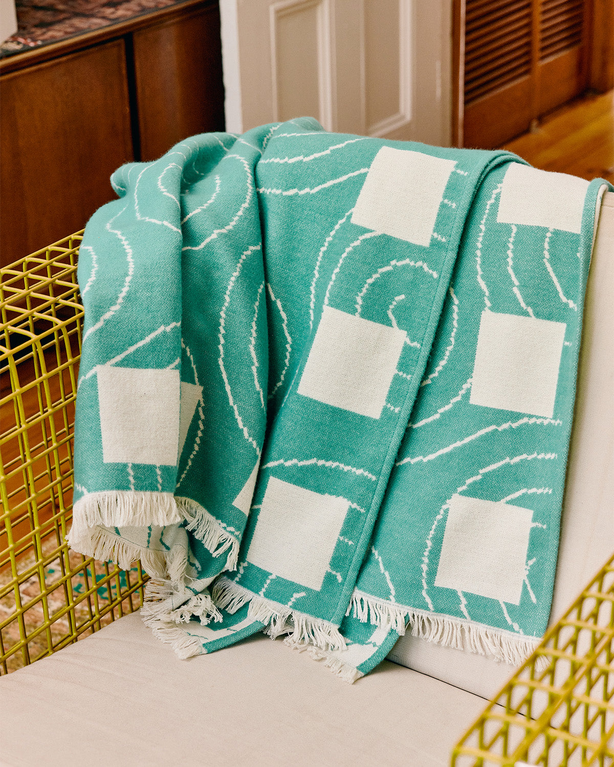 Teal and white patterned throw blanket draped over a chair in a home setting.