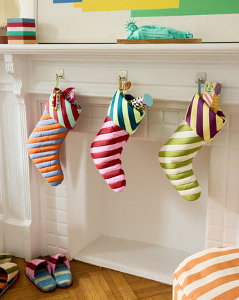 Colorful striped stockings hanging on a fireplace mantle with abstract art above. 