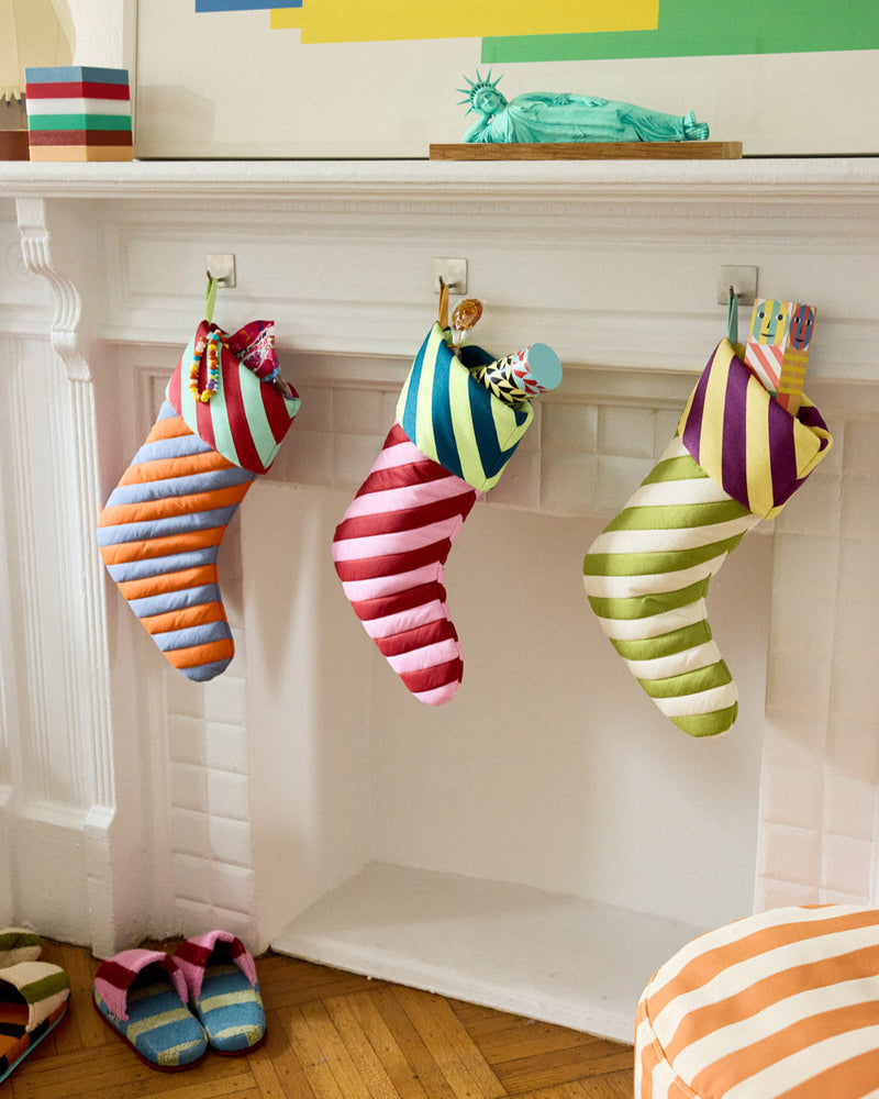 Colorful striped stockings hanging on a fireplace mantle with abstract art above. 