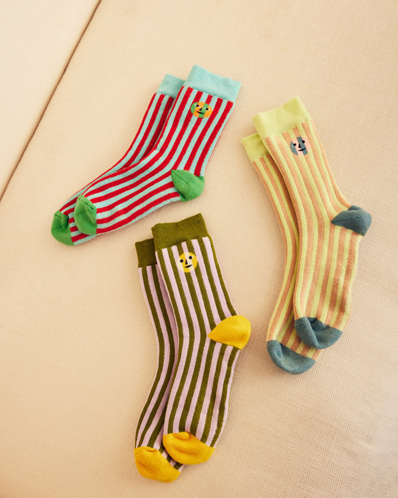 Three pairs of colorful socks with everybody face design on a beige background