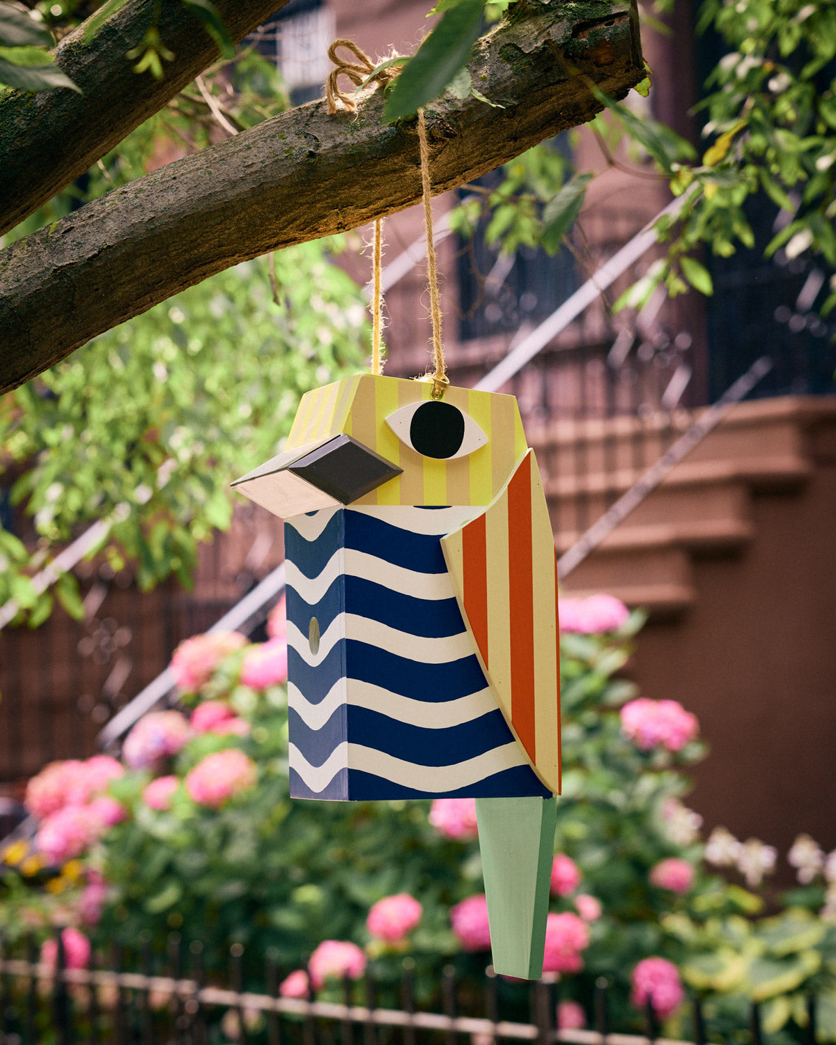 Striped Bird-shaped birdhouse hanging in a tree
