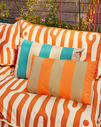 Outdoor sofa with orange and beige striped cushions and a turquoise pillow. 