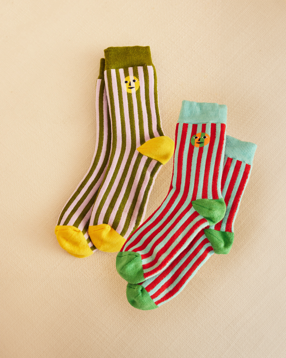 Two pairs of colorful socks with everybody face design on a beige background