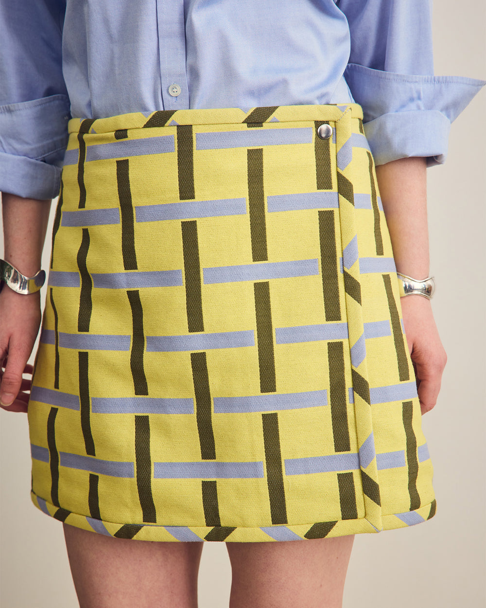 Person wearing a yellow skirt with blue and green pattern against a neutral background