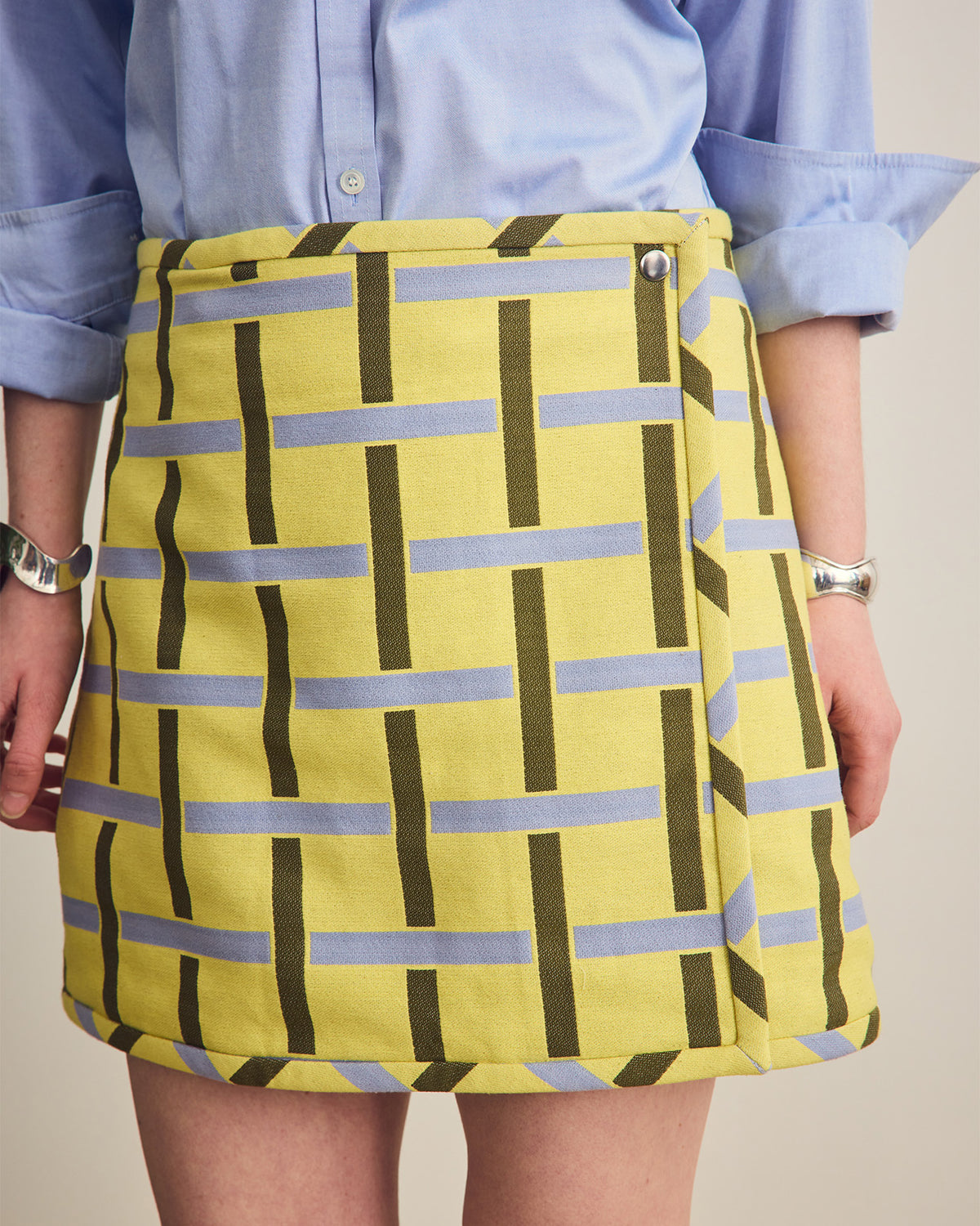 Person wearing a yellow skirt with blue and green pattern against a neutral background