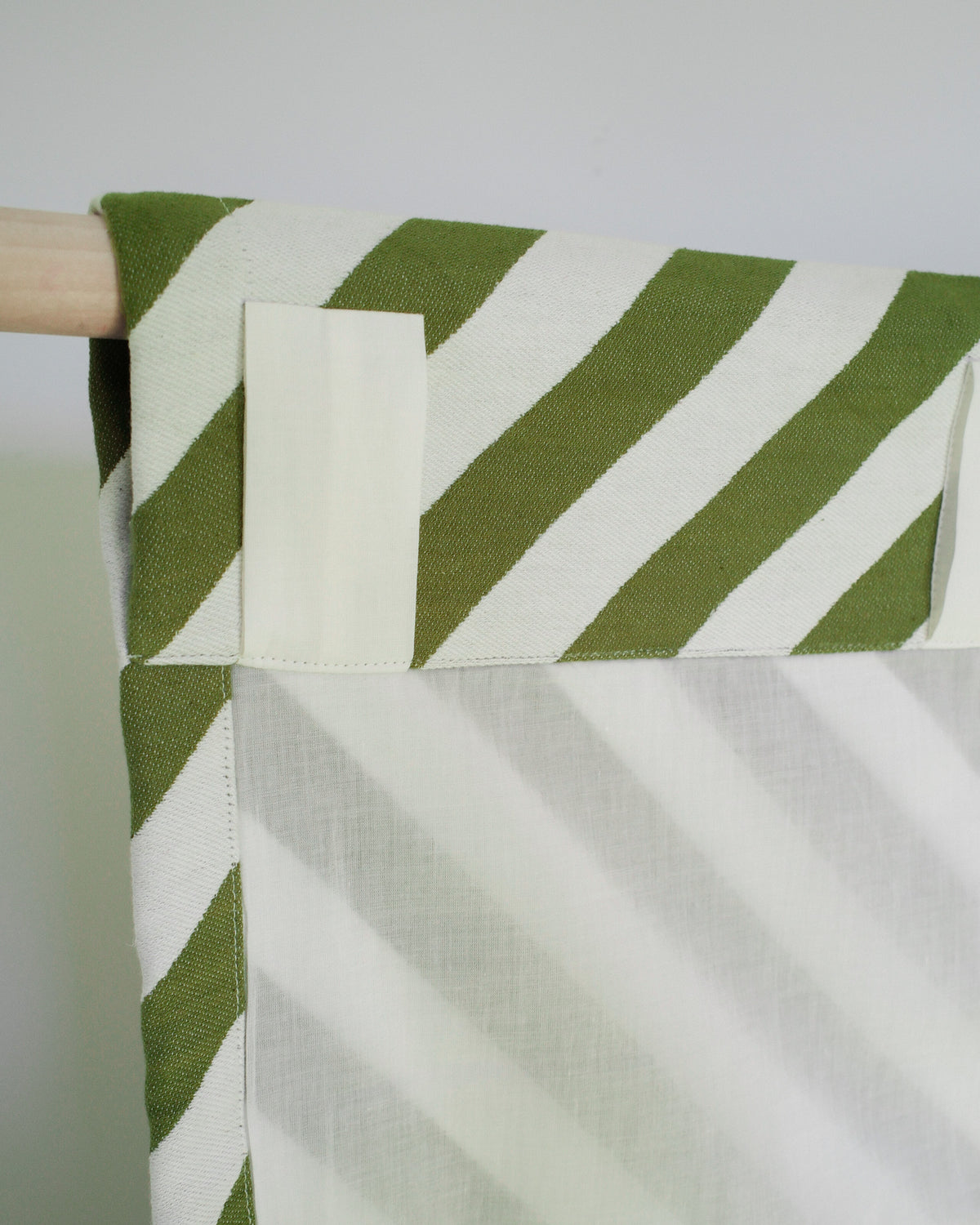 Green and white striped fabric on a wooden rod against a white background