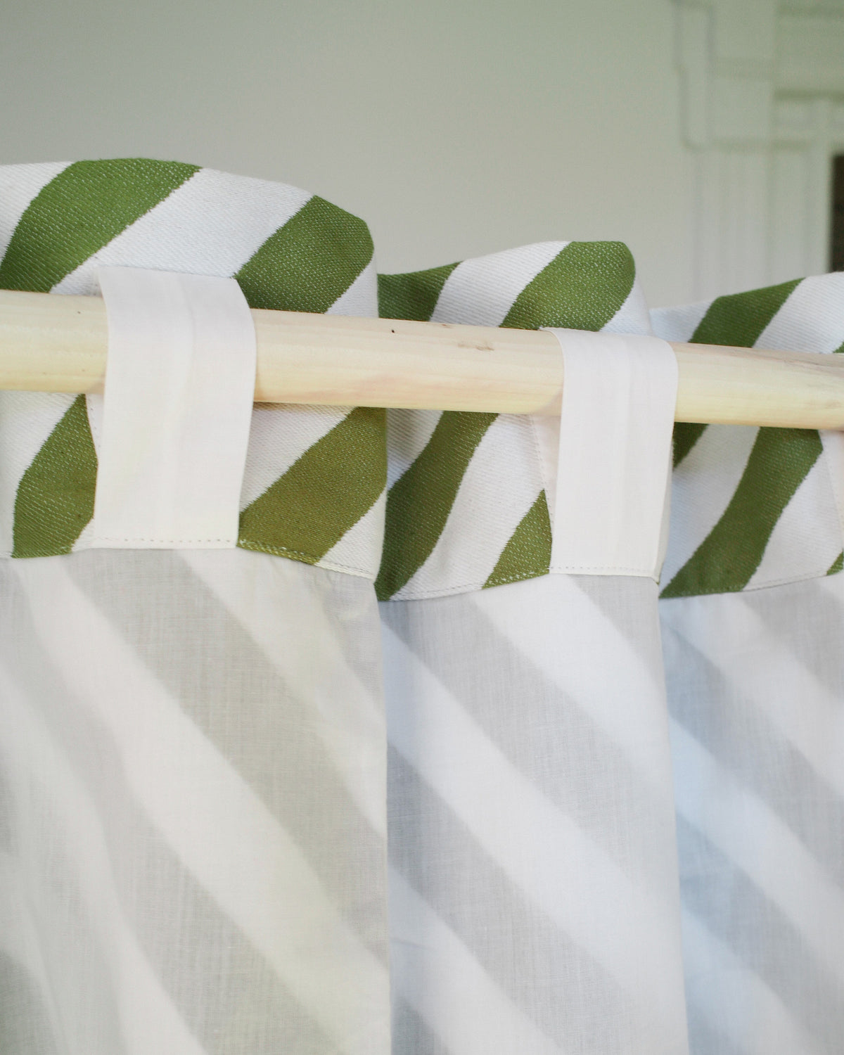 White curtain with green striped valance on a wooden rod against a white background