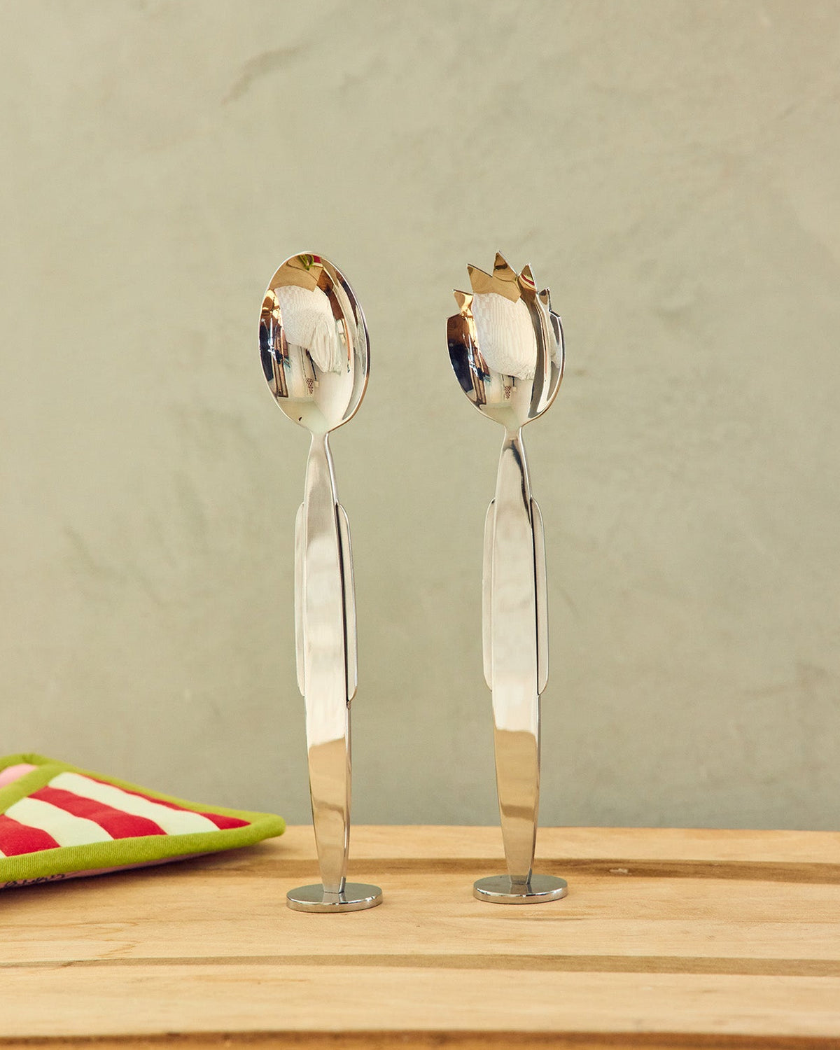 Serving spoon and fork on a wooden surface with a neutral background 