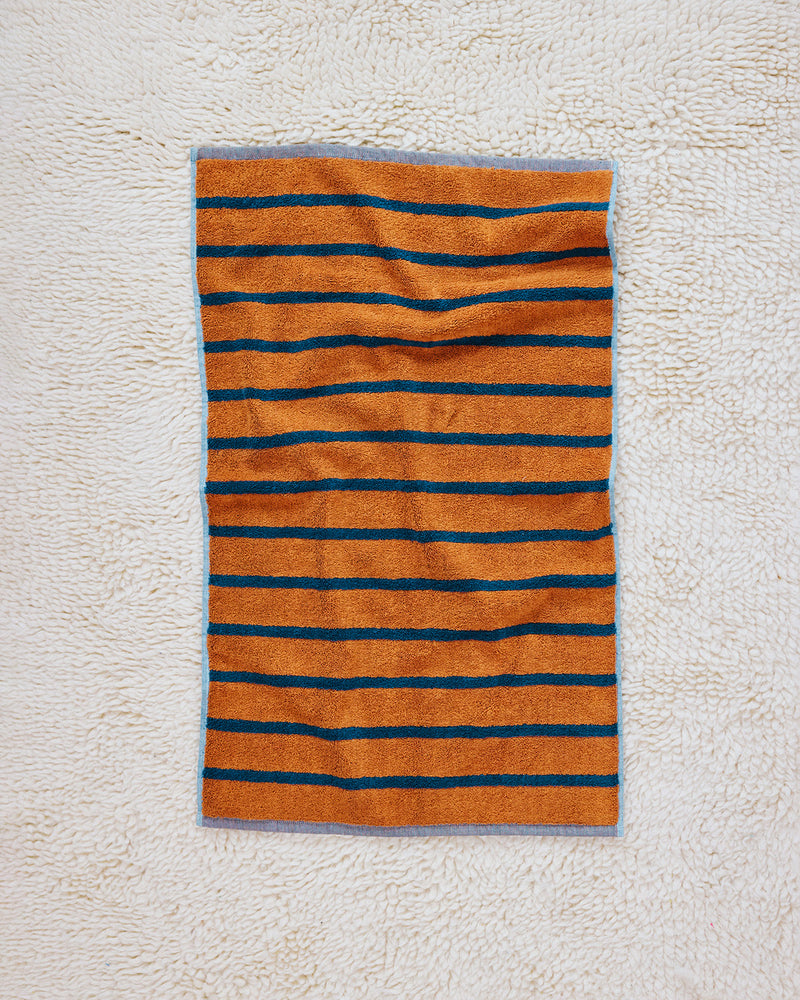 orange and navy striped towel on rug 