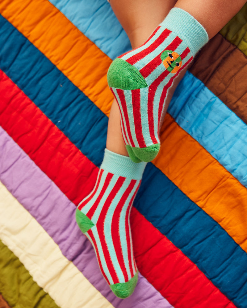 Warm stripe socks on a model with grene heel on a striped quilt