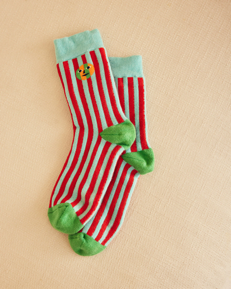 Red and light blue striped socks with green accents on a beige background
