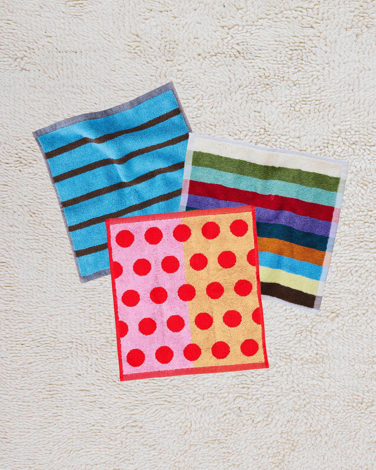 three colorful towels with different patterns on a textured surface 