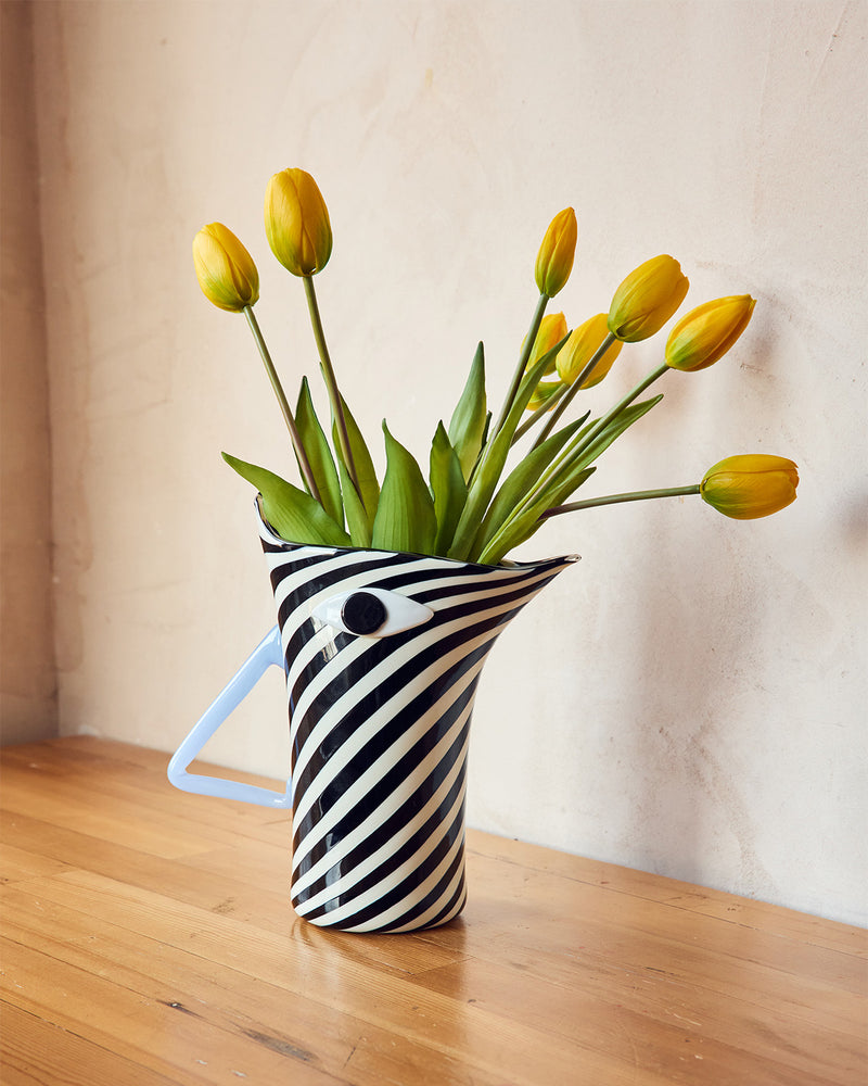 Black and white striped vase with yellow tulips on a wooden surface <br> <br> Hand-made in Murano, Venice, Italy by Laguna~B <br> <br>
Laguna~B is a Venice based company founded by Marie Brandolini in 1994