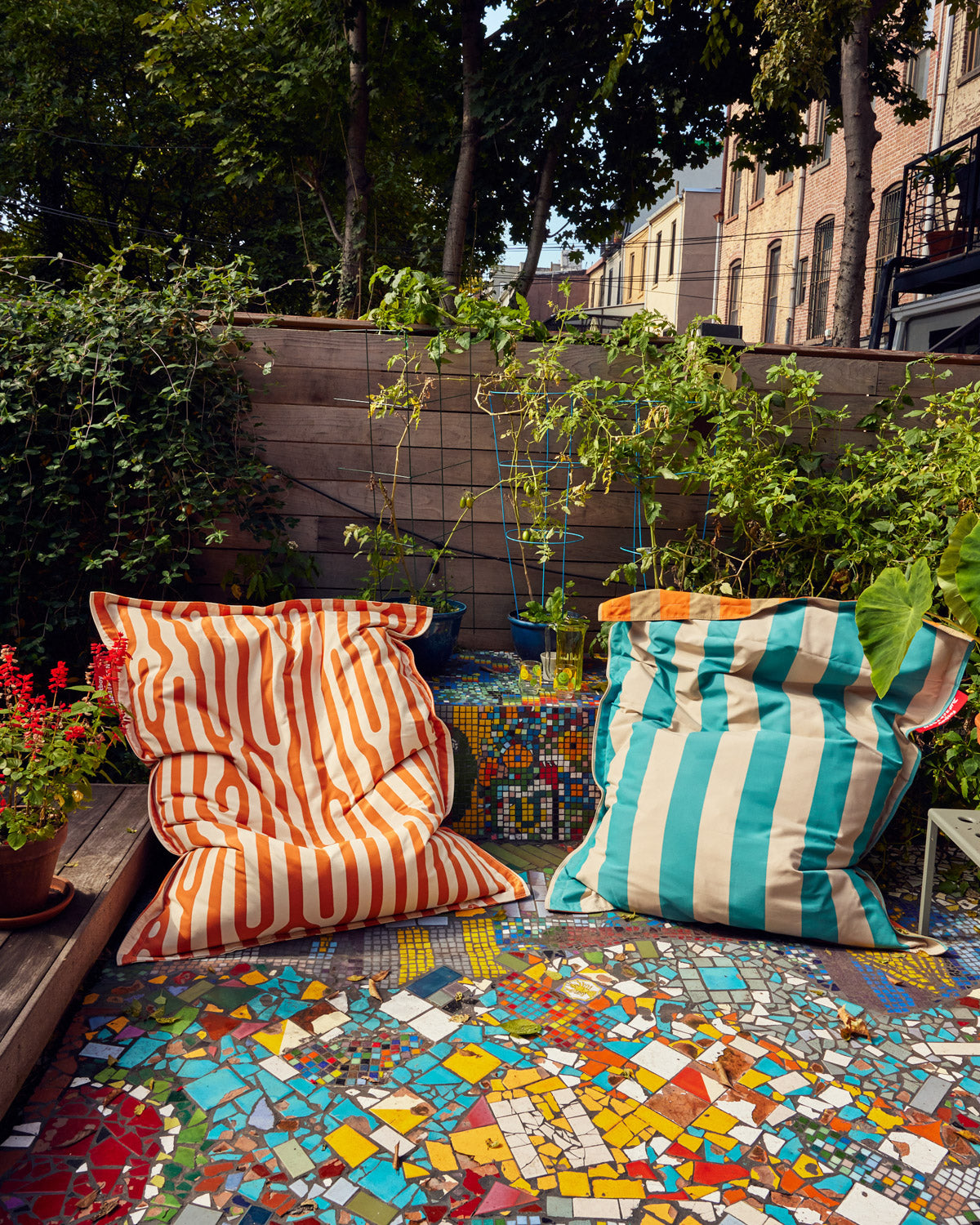 Fatboy x Dusen Dusen Outdoor Outdoor Slim Classic Bean Bag Chair in Stripe and Oak. One in Dark Brown and Orange, the other in white and blue based on the ground and sky. The other pattern in a rust and beige oak pattern. Two bean bags together in the yard