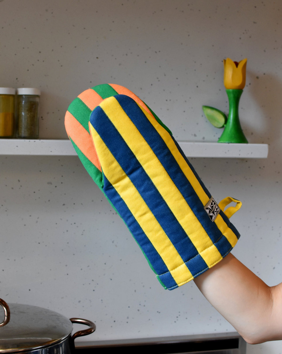 Dusen Dusen Carrot Oven Mitt. Padded oven mitt in varying stripe weights and contrasting stripe colorways. Features a "frog-style" mitt shape, top stitched brand label, and a side loop. 100% cotton quilted canvas base, with polyester fill.