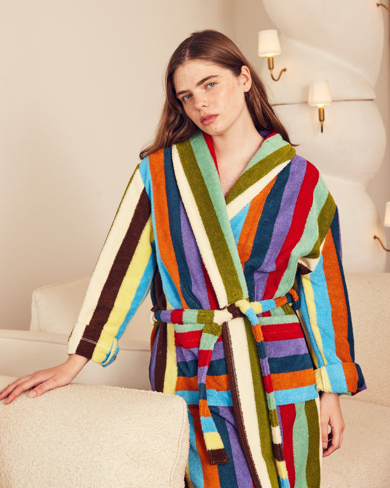 Woman wearing a colorful striped robe standing next to a couch