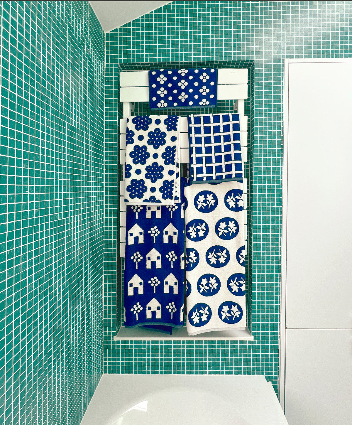 full set of navy towels in green tile bathroom