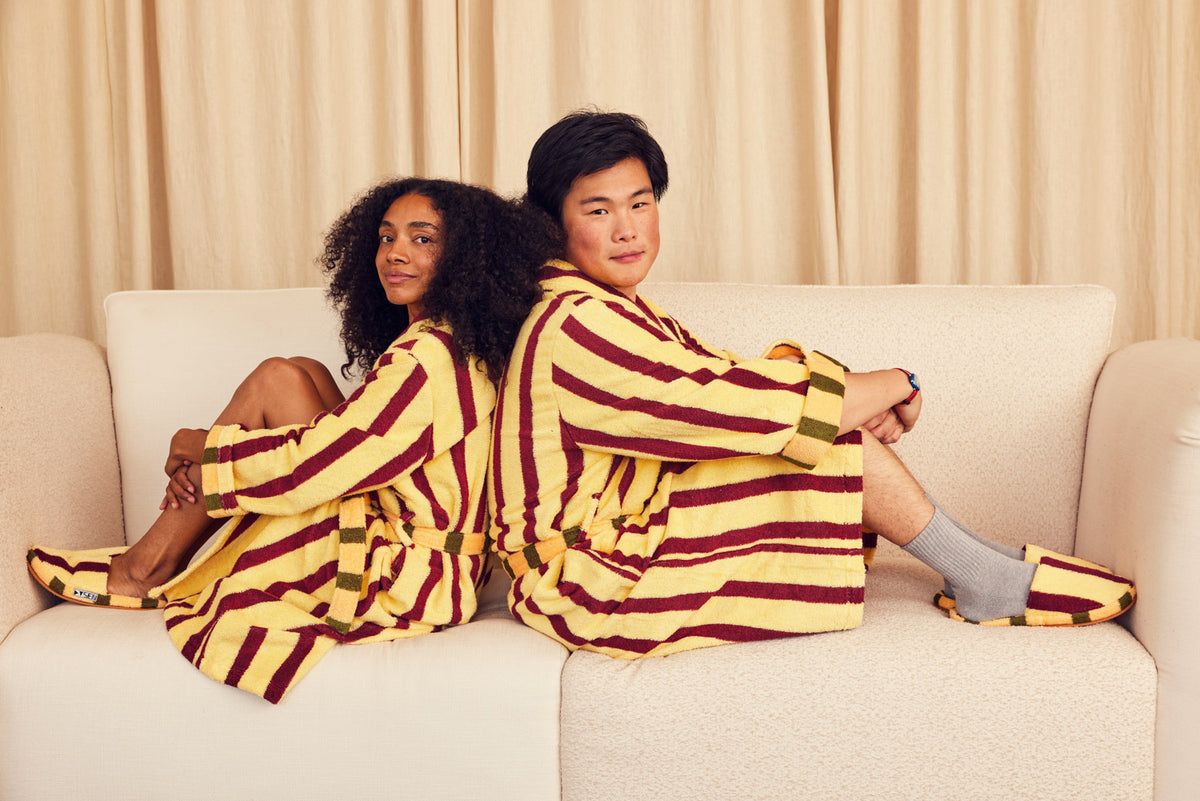 Two people in Ginkgo robes on couch back to back