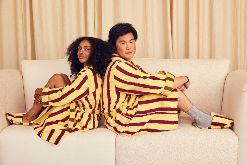 Two people in Ginkgo robes on couch back to back