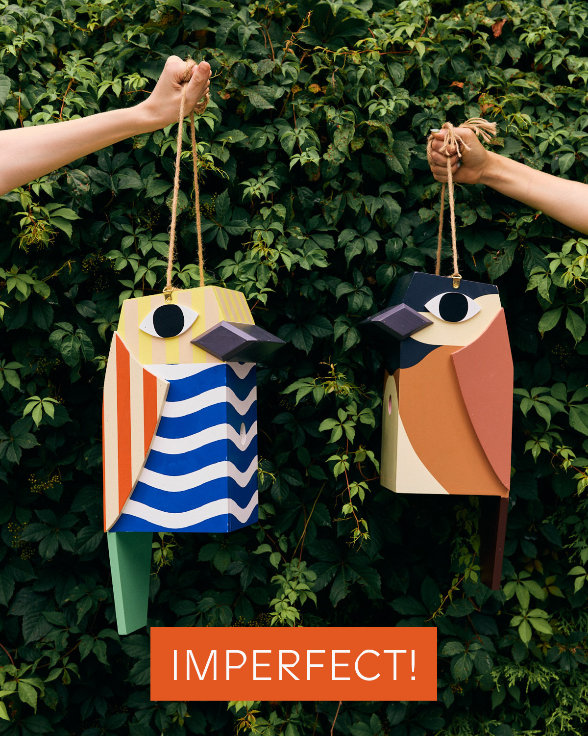 Two colorful birdhouses hanging against a green leafy background