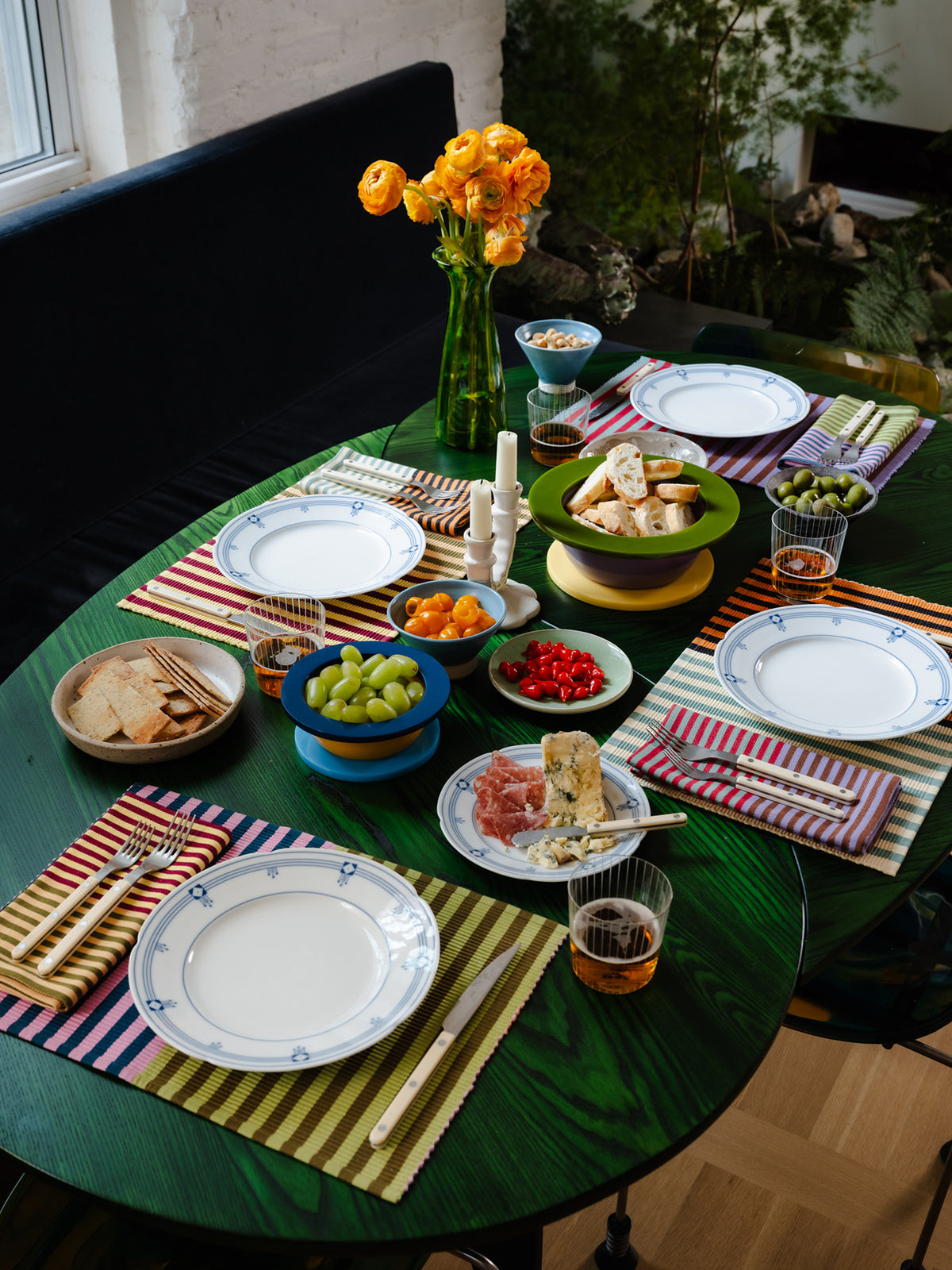 Set of four striped placemats on a green table with full spread of food