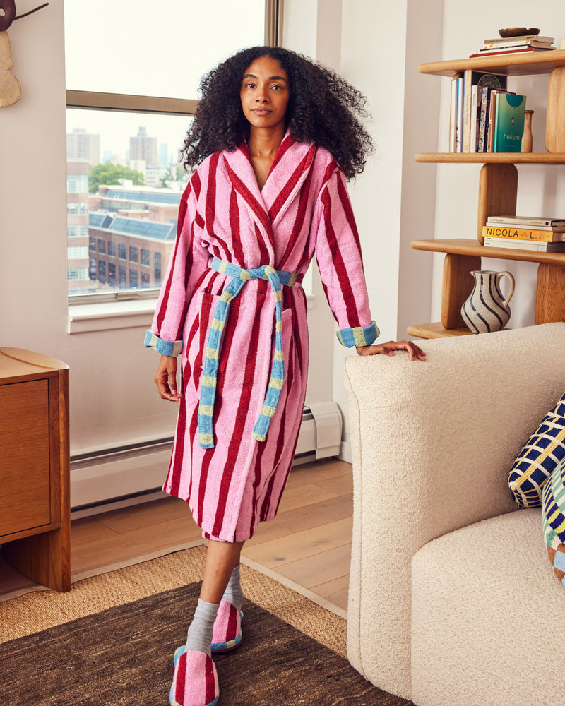 Shereen wearing a pink and red striped robe in a living room.