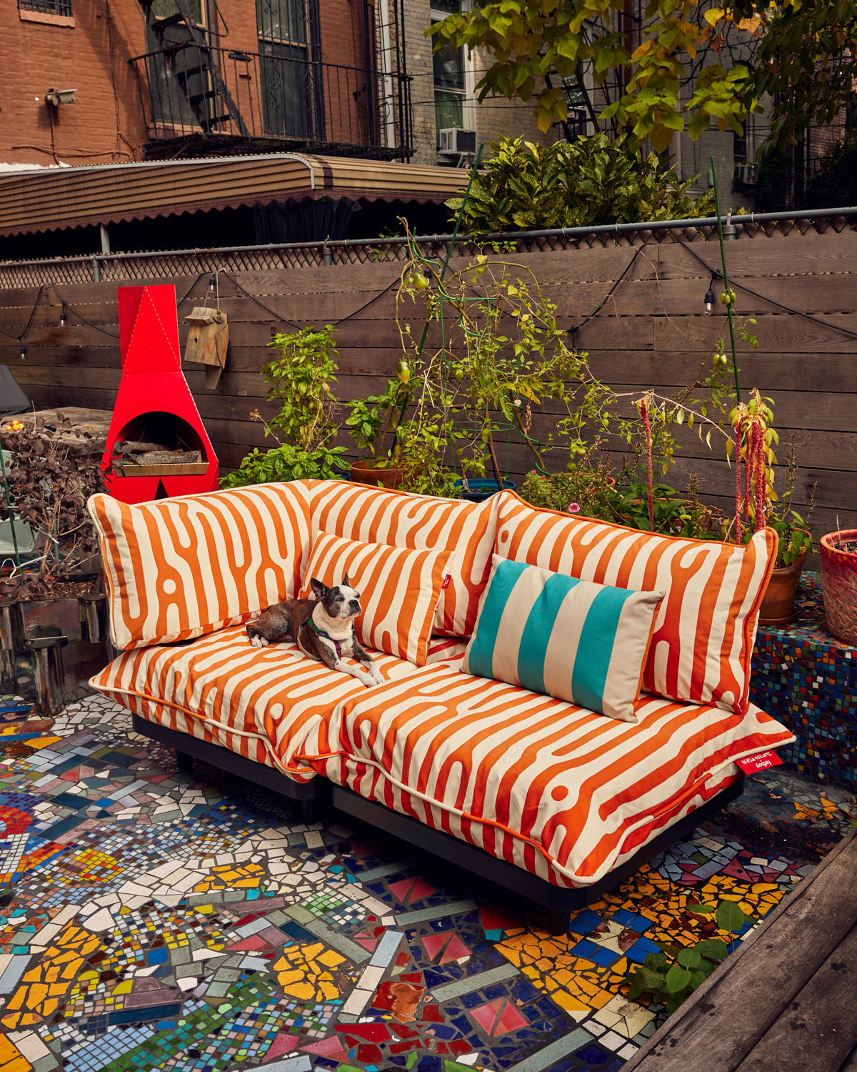 Fatboy x Dusen Dusen Outdoor King Pillow in Stripe and Oak. One in Dark Brown and Orange, the other in white and blue based on the ground and sky. Oak in orange-rust brown and white. UV-resistant, Water resistant, Stain resistant. oak pillow on couch; You will not get in trouble if you bring this pillow indoors