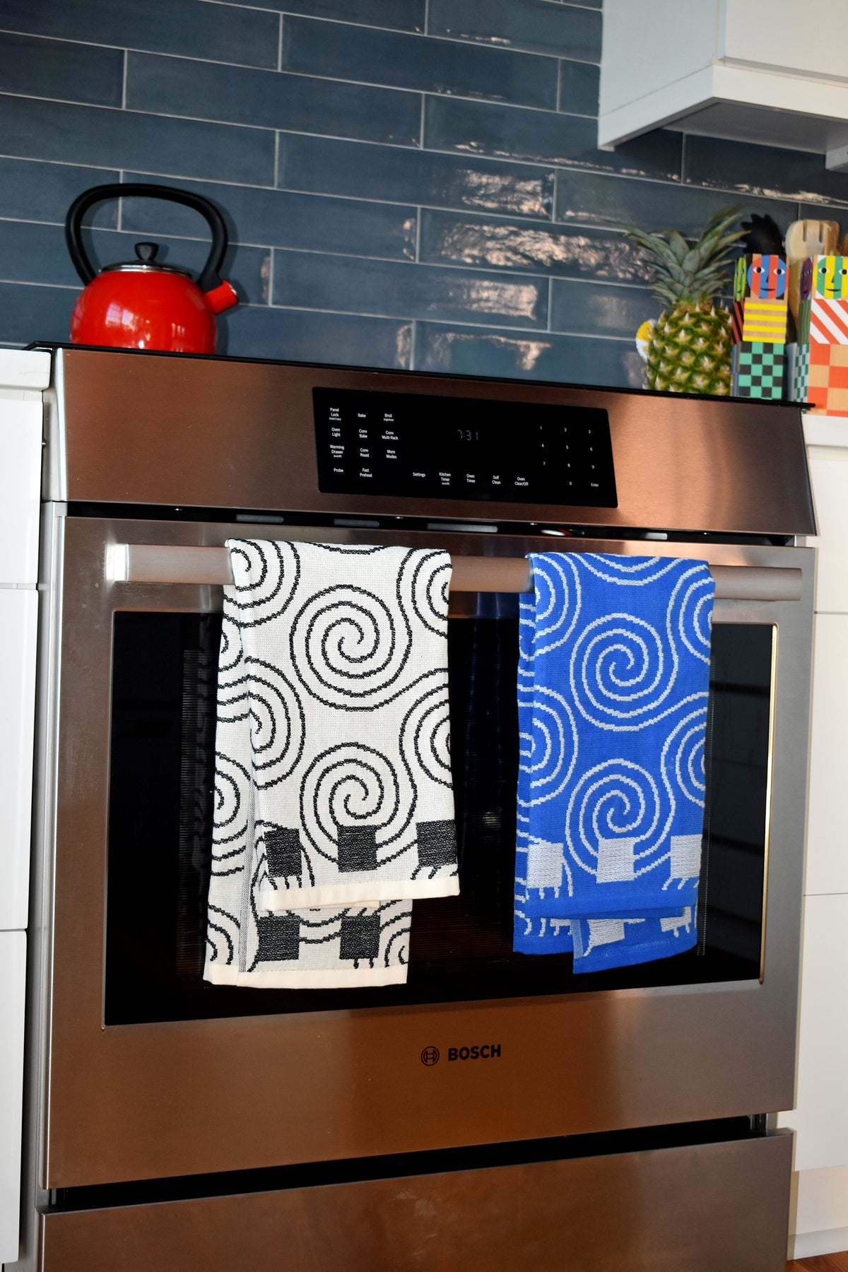 Two Spiral dish towels hanging over an oven handle