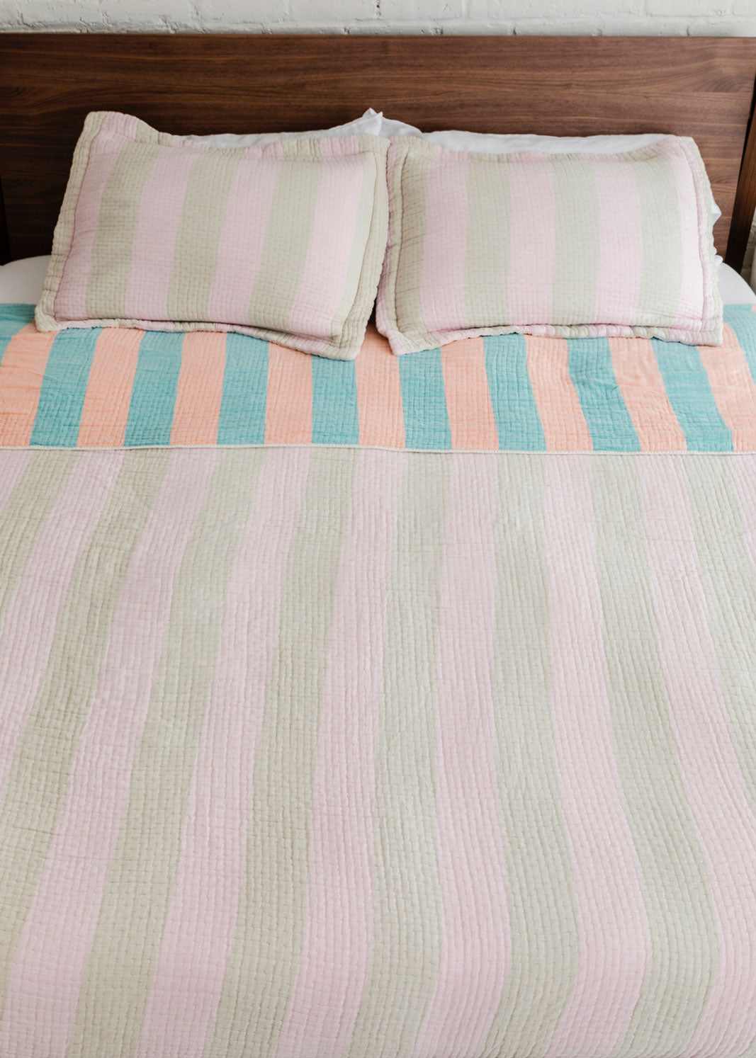 Dusen Dusen Warm Stripe Coverlet Set in reversible stripe colorways. Pink and beige stripes on one side, orange and green stripes on the other side. Woven matelassé coverlet with an inner layer of insulation for a quilted effect. Stonewashed, with an extra soft and gauzy hand feel. 100% cotton shell, polyester fill. Machine wash cold and tumble dry low. Made in Portugal. 