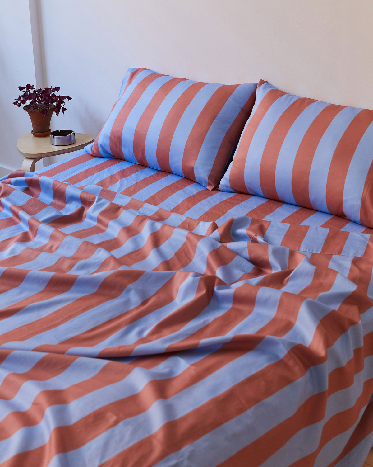 Dusen Dusen Canyon Stripe Sheets. Sheeting in soft blue and terra cotta stripes. 100% cotton sateen, 300 thread count. Machine wash cold and tumble dry. Made in Portugal. Our cotton sateen is smooth and cool to the touch and features a slightly lustrous finish.