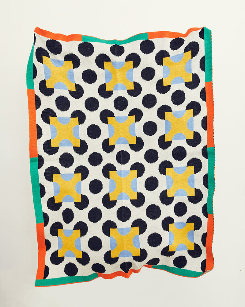 Dusen Dusen Throw in Dot pattern. Cotton knit throw in black and white with contrasting yellow and cornflower blue dot print and an orange and green border. 100% cotton, medium weight, soft & cozy. 50" W x 70" H. Machine wash cold, tumble dry low. Made in China