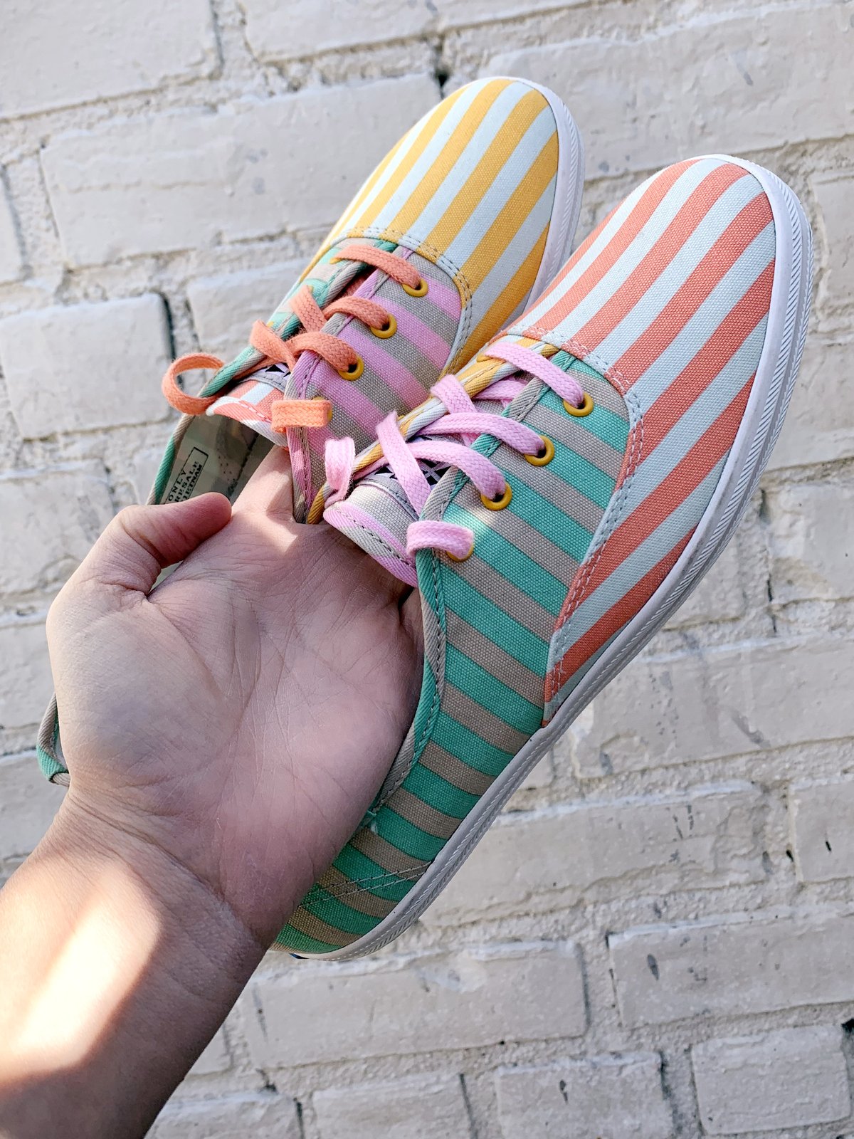 striped keds being held