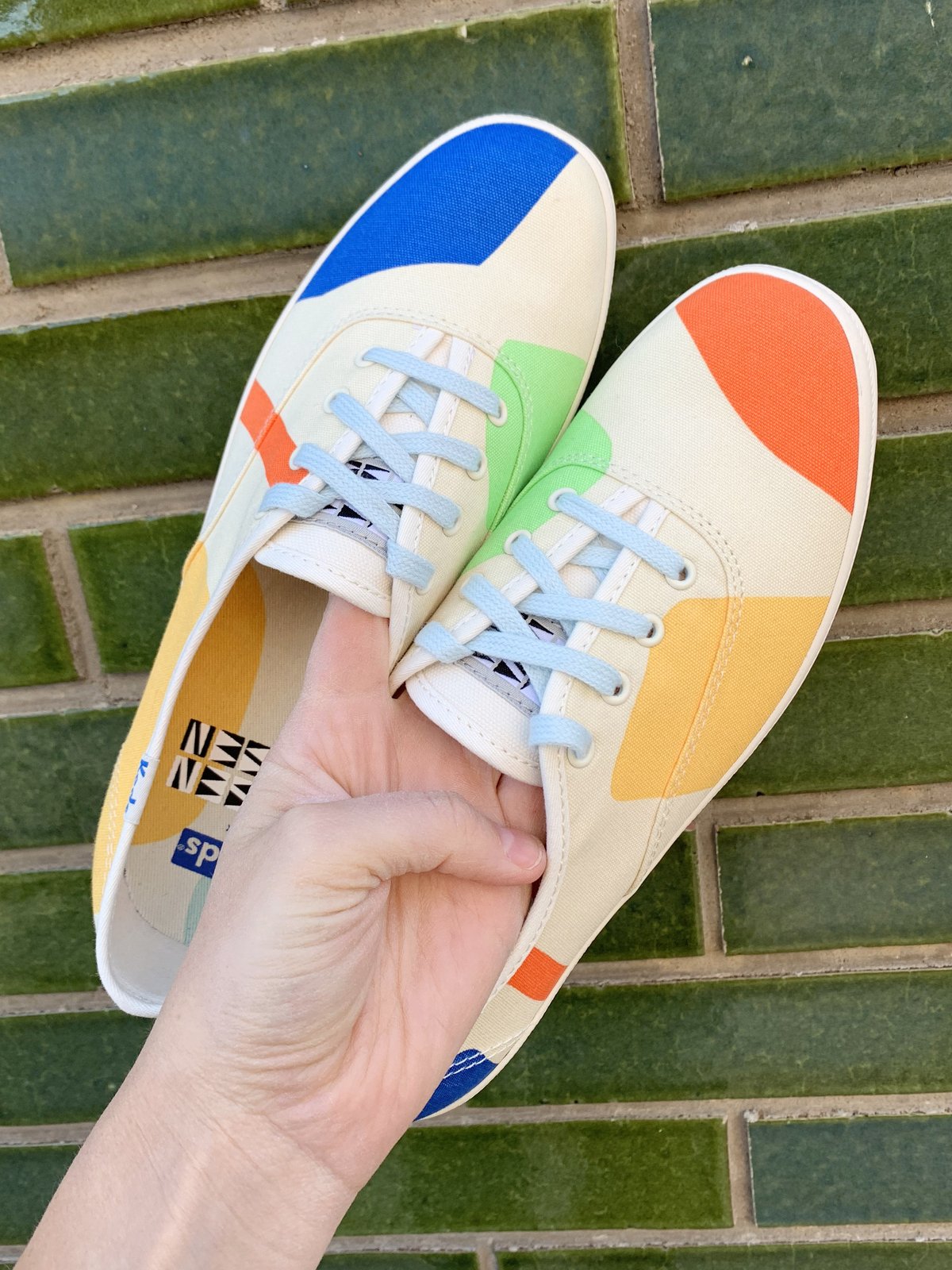 beige shoes with colorful blocks on keds being held