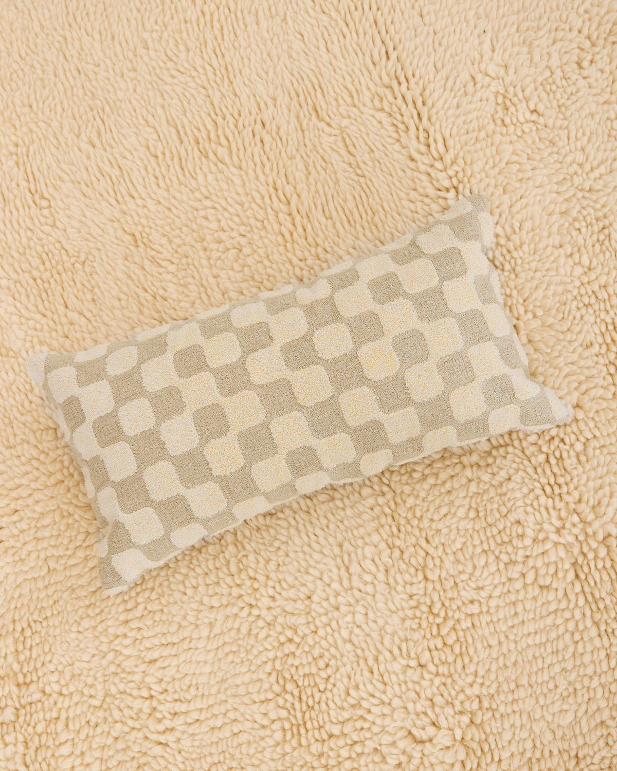 Dusen Dusen Net Pillow. 100% cotton embroidery and tufting bolster pillow in beige and cream Net pattern. Non-embroidered natural canvas back with a zipper opening. Available as 12" x 22". Spot clean only. Made in India.