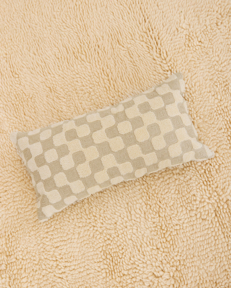 Dusen Dusen Net Pillow. 100% cotton embroidery and tufting bolster pillow in beige and cream Net pattern. Non-embroidered natural canvas back with a zipper opening. Available as 12" x 22". Spot clean only. Made in India.