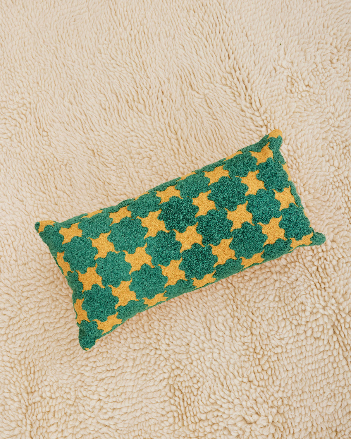 100% cotton embroidery and tufting bolster pillow in green and mustard Sun pattern. Non-embroidered natural canvas back with a zipper opening. Available as 12" x 22". Spot clean only. Made in India.