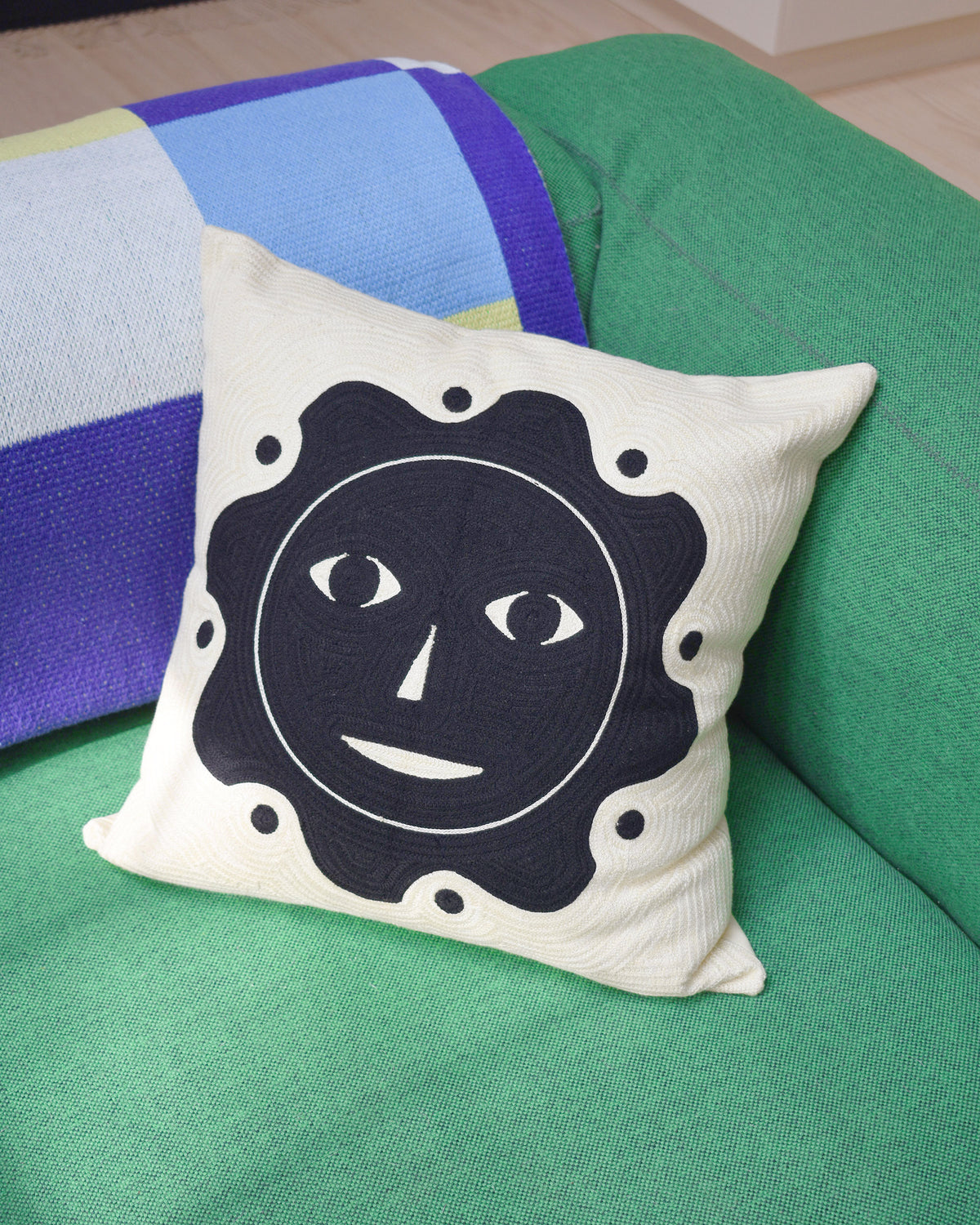 Dusen Dusen Everybody Sun Pillow. Embroidered pillow with Everybody Sun Face. 100% cotton, back zip, non-embroidered natural canvas back. Available as 18" x 18". Spot clean only. Made in India. Pillow insert is a polyfill-down alternative and mimics the fluffiness of natural down. Insert is made in the USA.