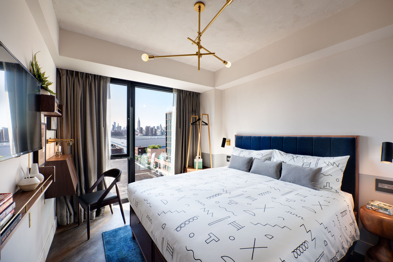 wide shot of hotel room with black line pattern on white sheets