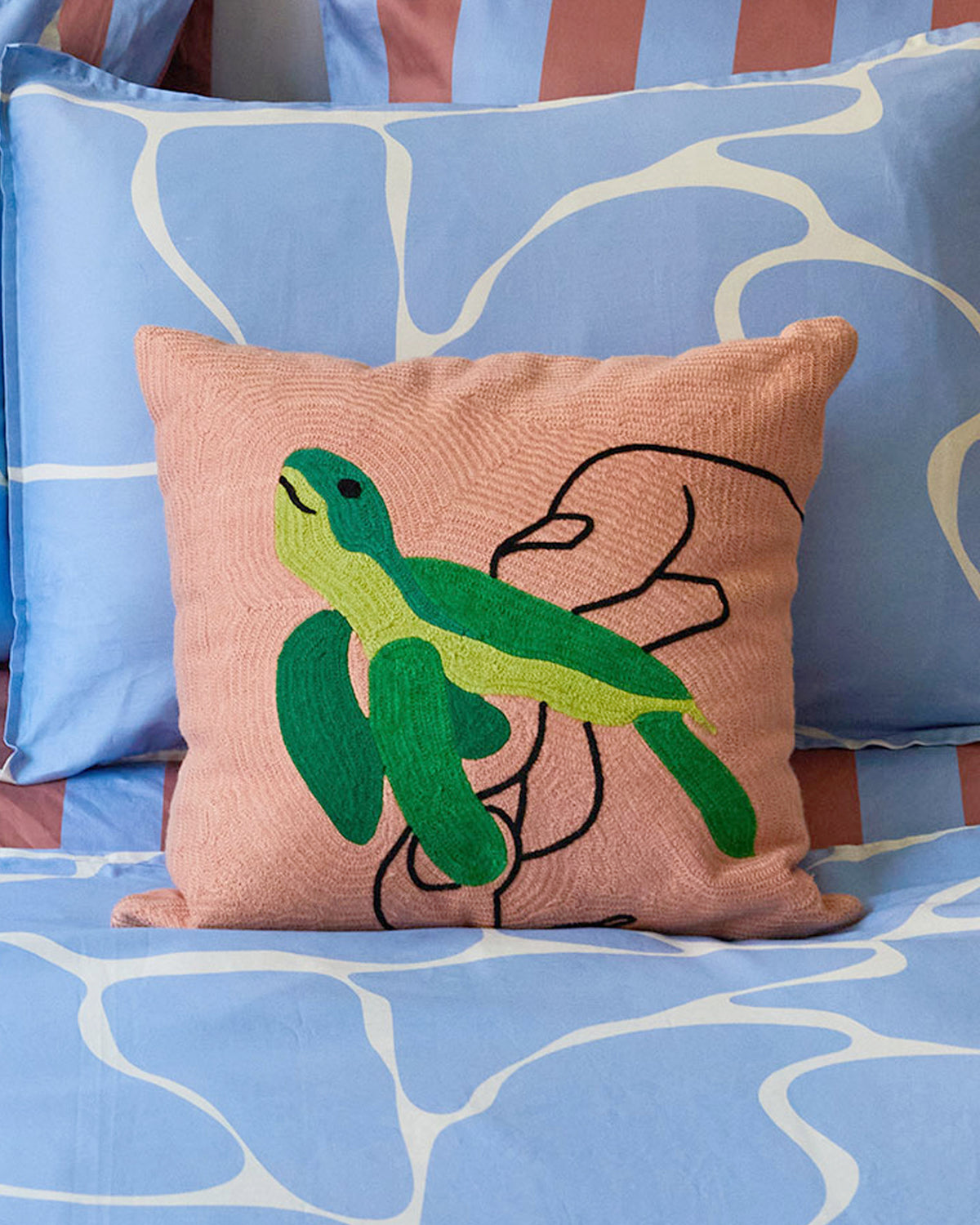 Dusen Dusen Turtle Pillow. Embroidered pillow with green Turtle icon on peach background. 100% cotton, back zip, non-embroidered natural canvas back. Available as 18" x 18". Spot clean only. Made in India.  Pillow insert is a polyfill down alternative and mimics the fluffiness of natural down. Insert is made in USA.