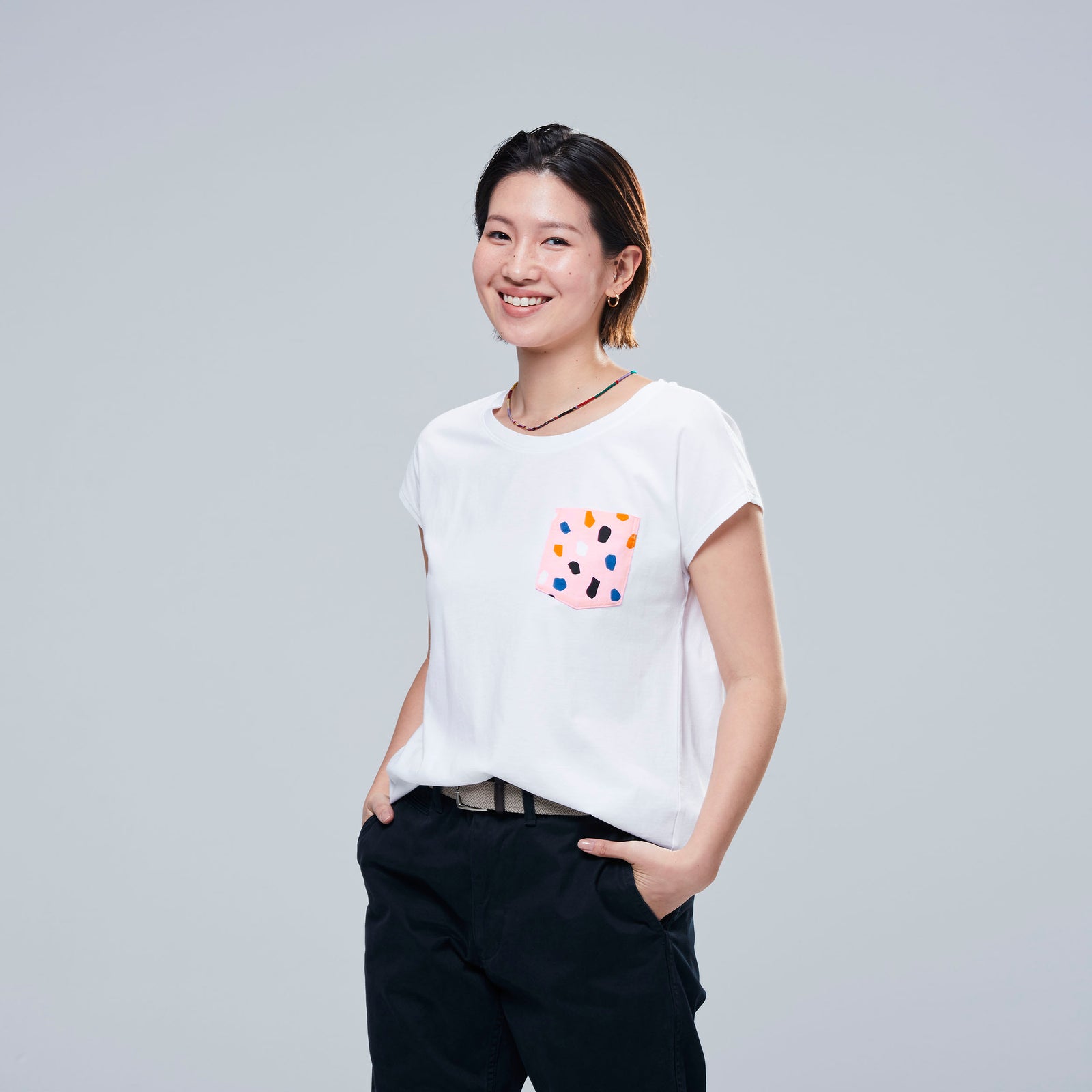 woman in white t shirt with pink pattern detail on pocket