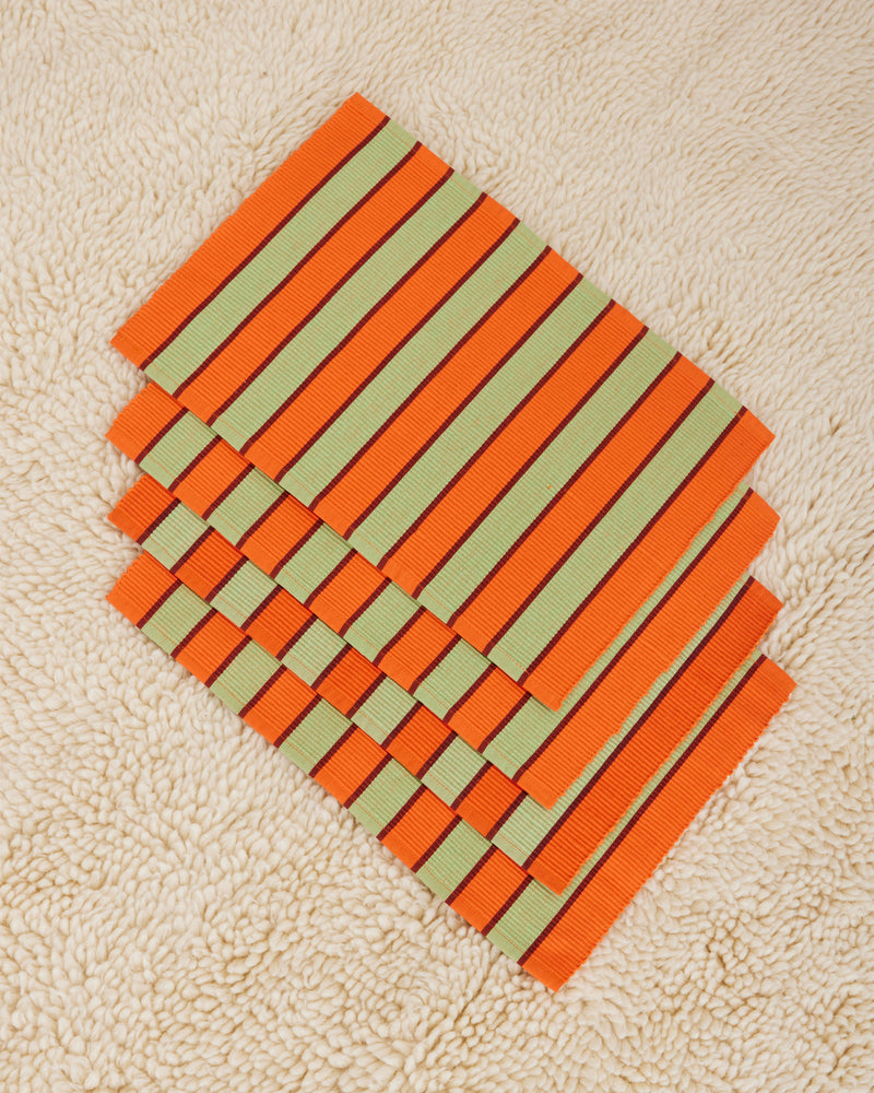 Dusen Dusen Orange Pesto Striped Placemats Set of 4. Cotton placemats in tri-color stripes with a ribbed texture. 100% cotton, 12" x 18". Machine wash cold and lay flat to dry. Spot clean as needed. Made in India.
