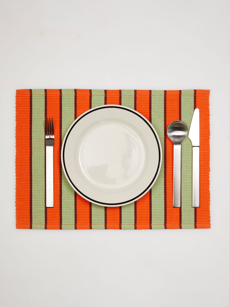 Dusen Dusen Orange Pesto Striped Placemat. Cotton placemats in tri-color stripes with a ribbed texture. 100% cotton, 12" x 18". Machine wash cold and lay flat to dry. Spot clean as needed. Made in India.
