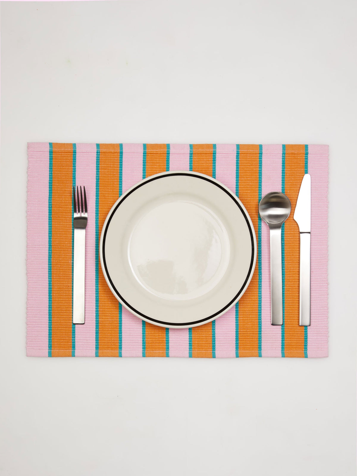 Dusen Dusen Proscuitto Striped Placemat. Cotton placemats in tri-color stripes with a ribbed texture. 100% cotton, 12" x 18". Machine wash cold and lay flat to dry. Spot clean as needed. Made in India.