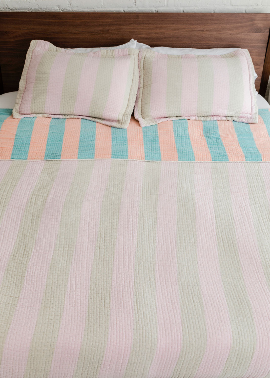 Dusen Dusen Warm Stripe Coverlet Set in reversible stripe colorways. Pink and beige stripes on one side, orange and green stripes on the other side. Woven matelassé coverlet with an inner layer of insulation for a quilted effect. Stonewashed, with an extra soft and gauzy hand feel. 100% cotton shell, polyester fill. Machine wash cold and tumble dry low. Made in Portugal.  Coverlet and shams are sold separately;